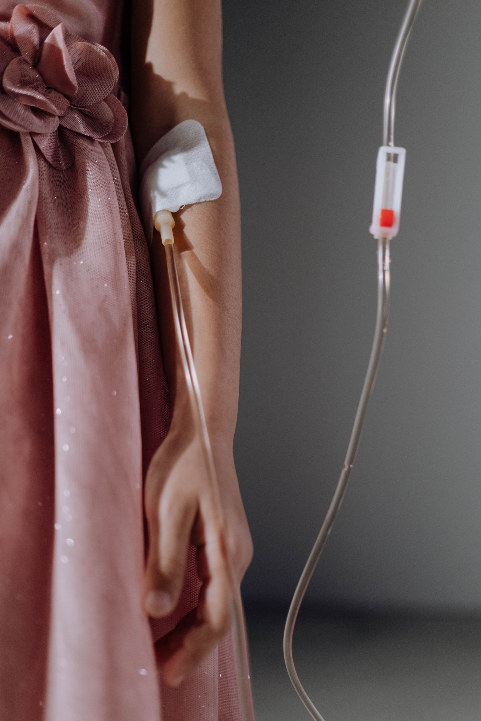 Close-up of an IV line connected to a person's arm, with the fluid bag visible in the background