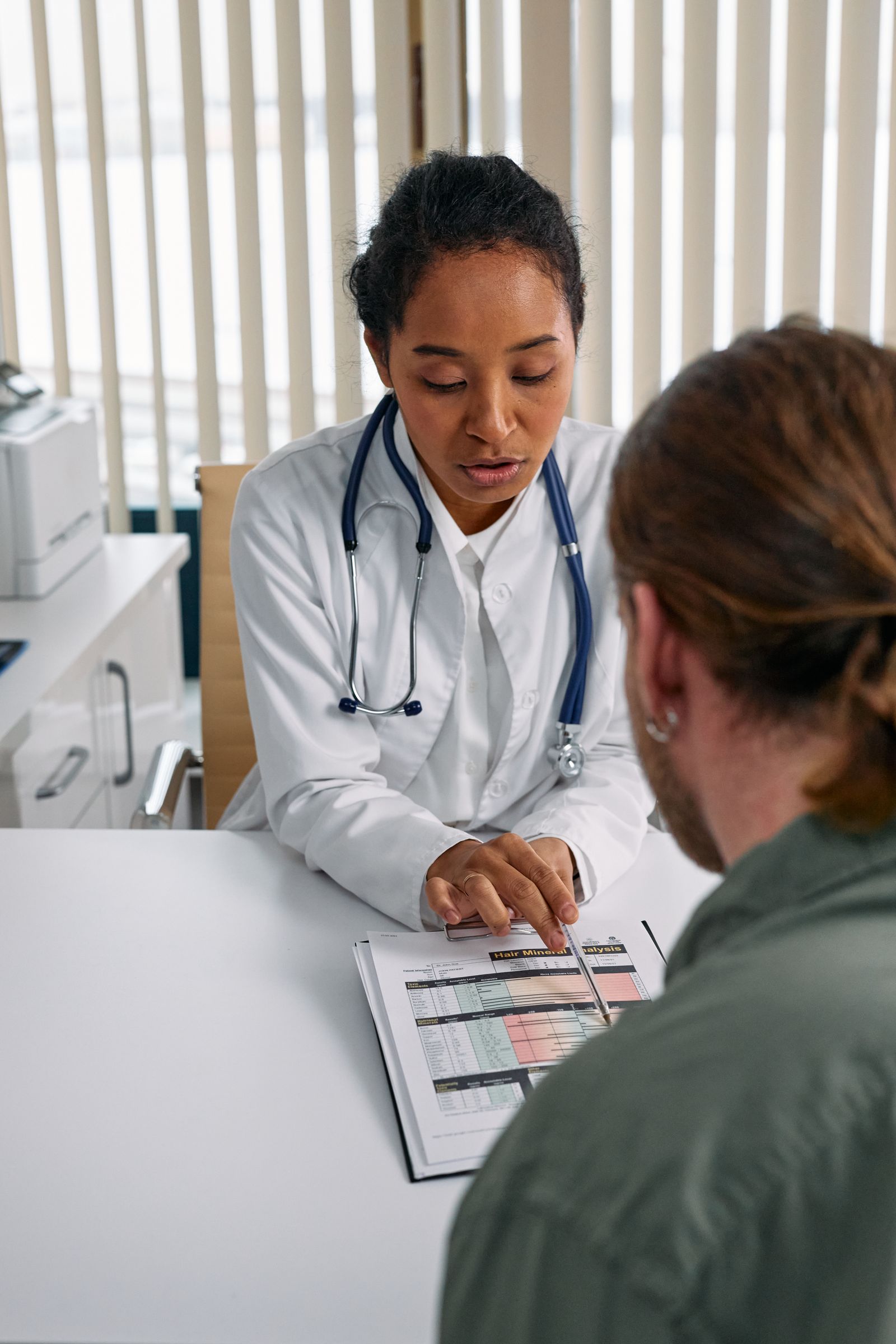 A doctor reviews a chart with a patient, pointing to results on the desk